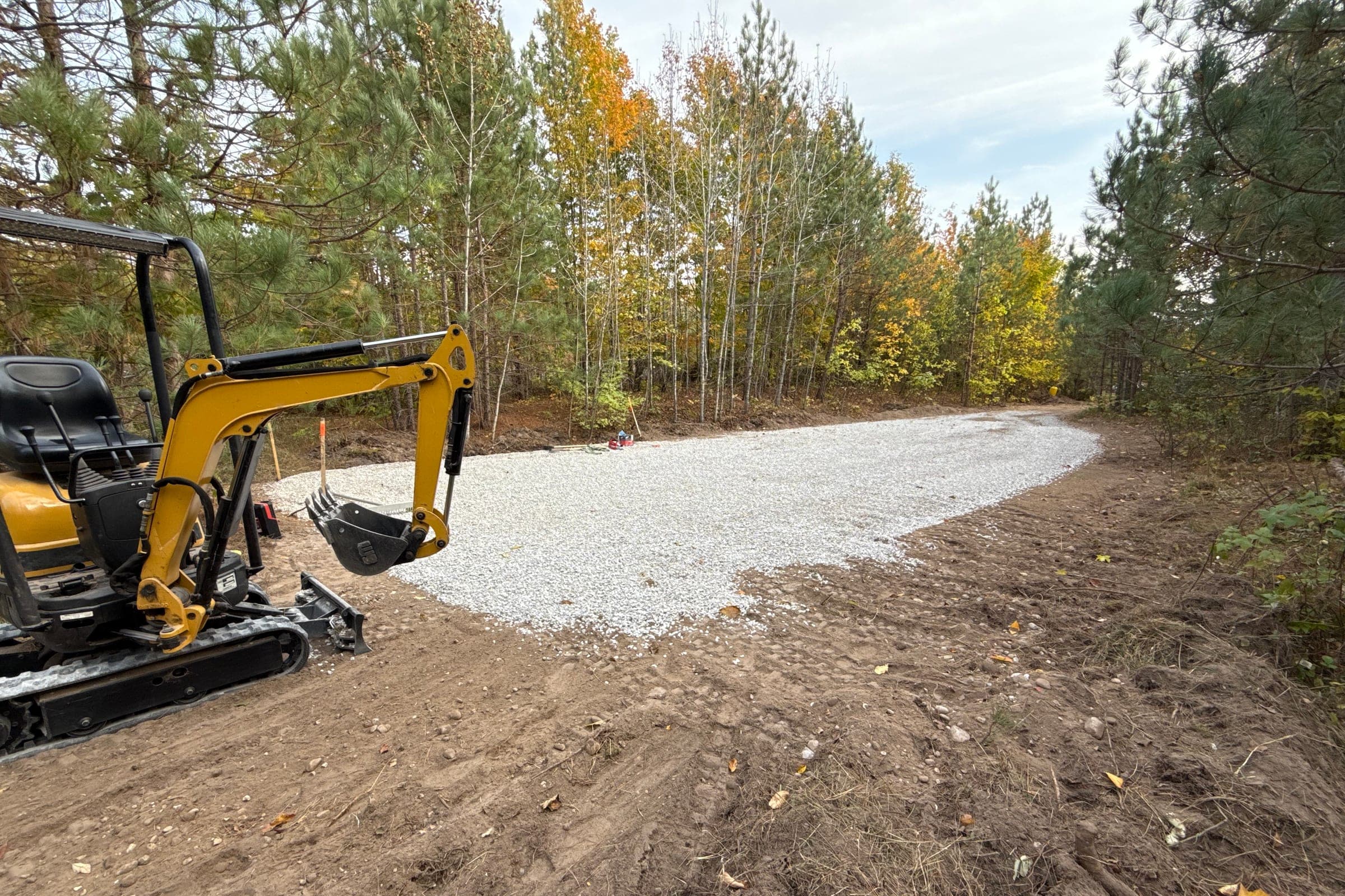 Mini excavator beside a newly installed gravel driveway