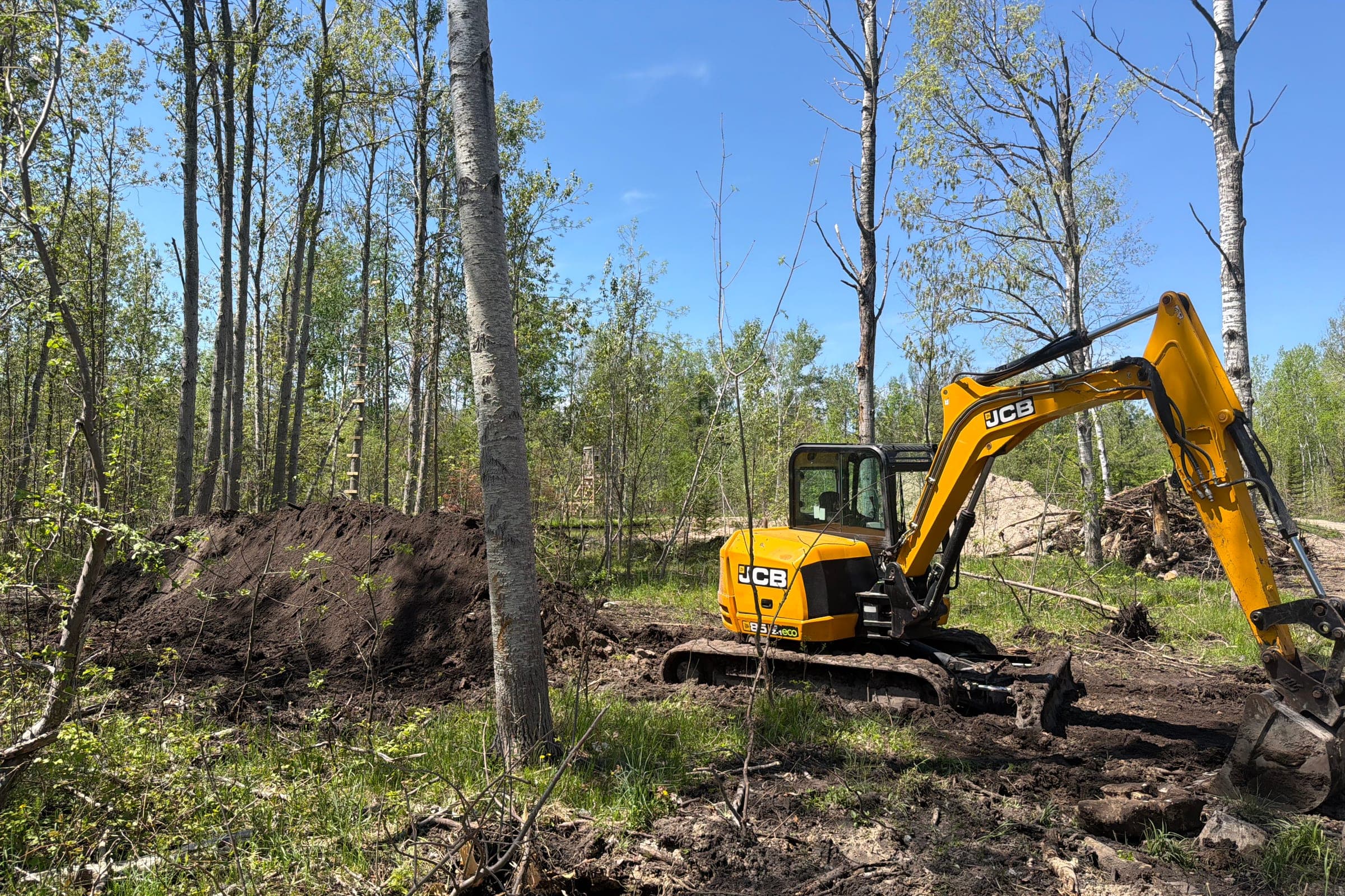 Northern Dirt excavator working on a wooded job site