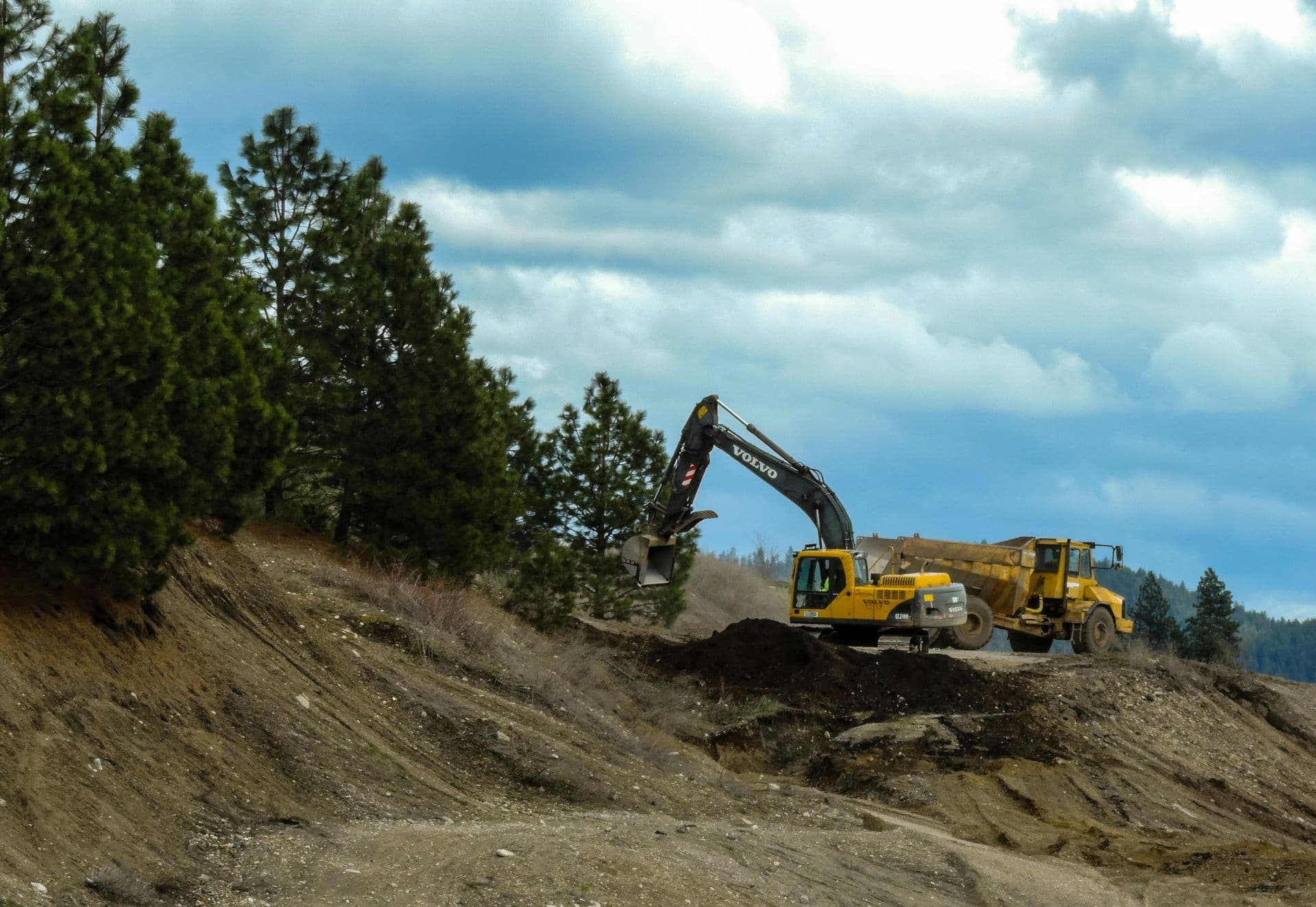 Excavator and dump truck working on a wooded earthwork site