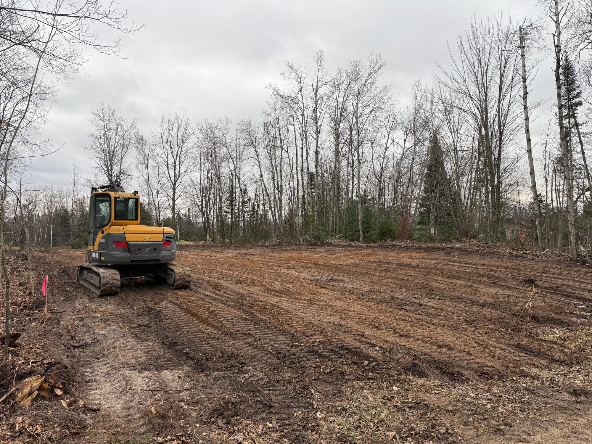 Excavator grading a large cleared construction area