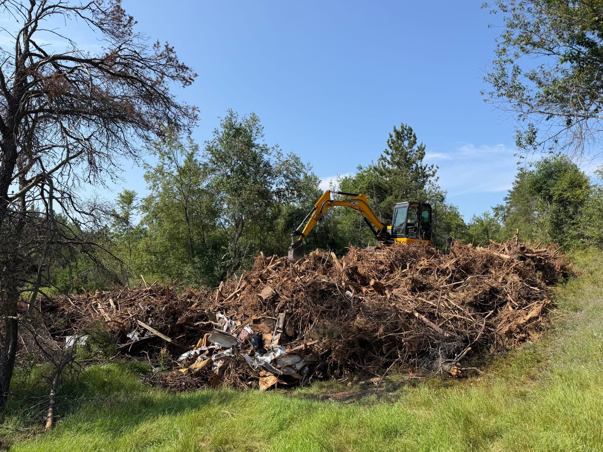 Large root and tree debris pile being removed from a property